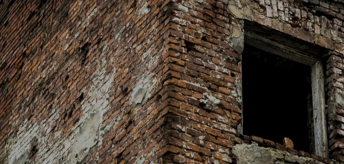Dark open window in a rough brick wall